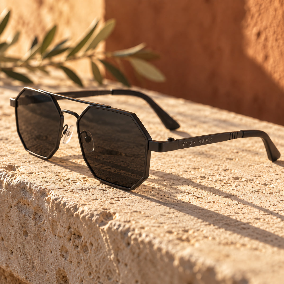 ROSHFORT Noir Hexa personalised sunglasses on a limestone ledge, your name engraved on the temple