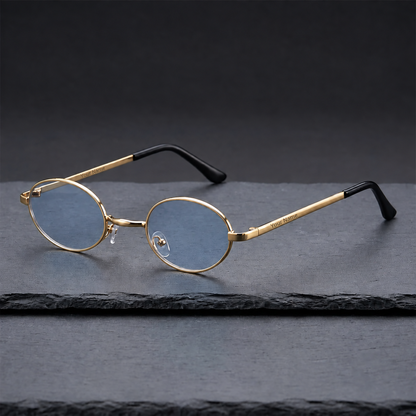 Gold-tone oval sunglasses with pale blue lenses and black temple tips, viewed at an angle on dark slate.