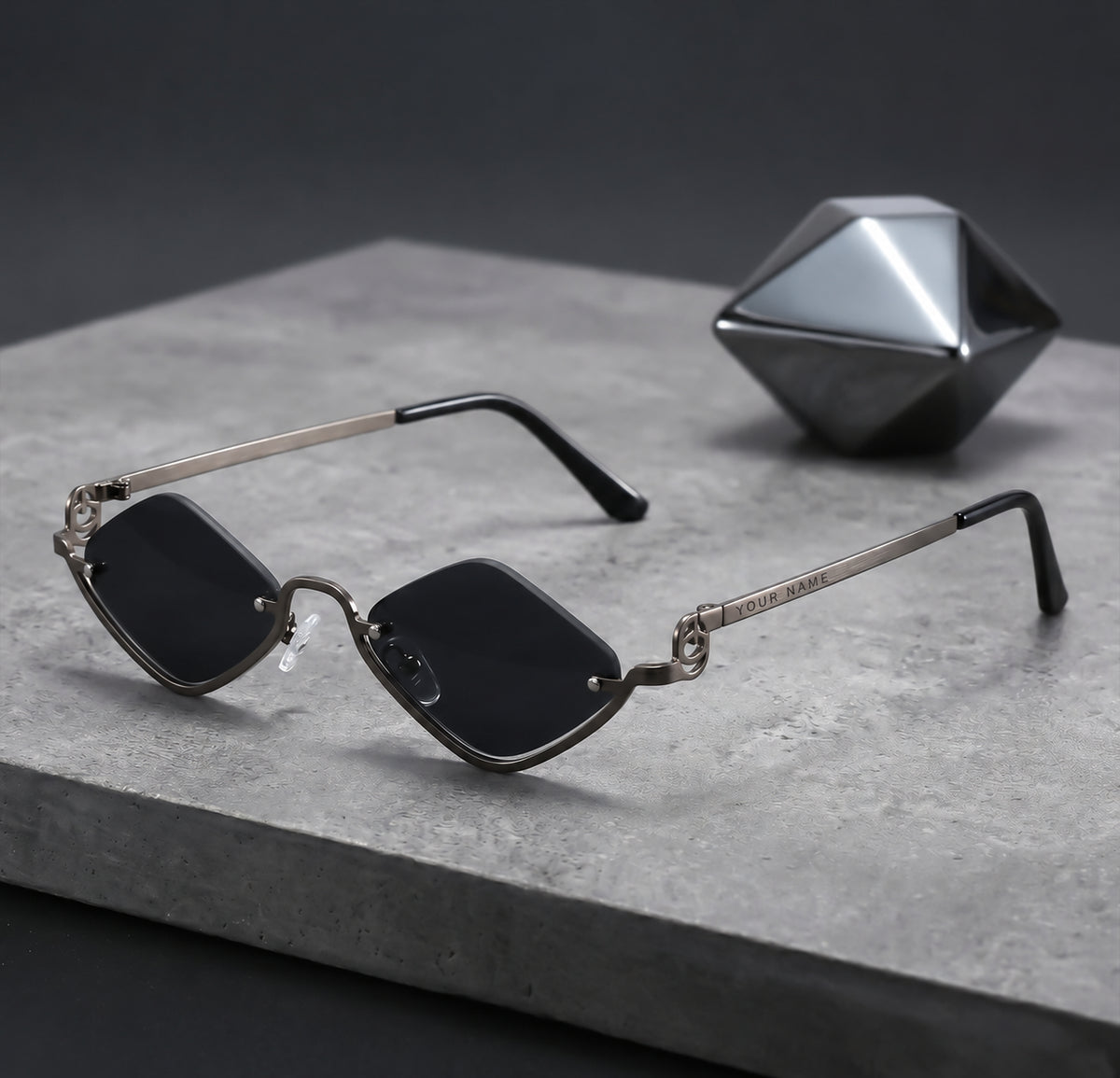 ROSHFORT Noir Facet sunglasses on a stone slab, your name engraved on the temple