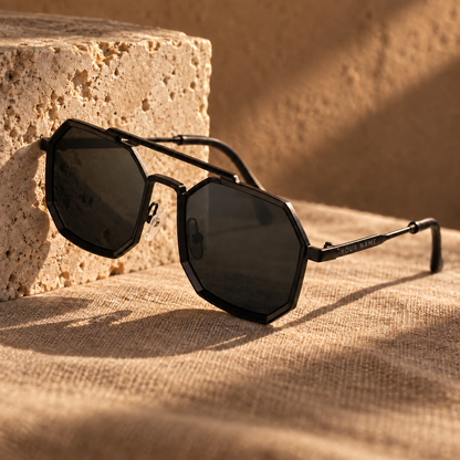 ROSHFORT Noir Hexa personalised sunglasses against a travertine block, your name engraved on the temple