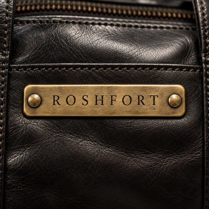 Close-up of the aged brass ROSHFORT name plate riveted to the black crunch leather